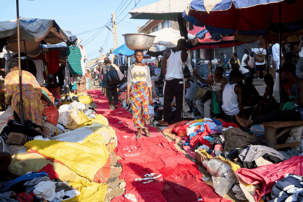 Artist and kayayei collaborators weaving textile headpieces inside Kantamanto Market as part of the Okrika Reclaimed installation.