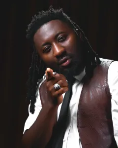 Ghanaian musician Amerado in a confident pose, dressed in stylish urban wear, with dreadlocks and a focused expression, representing his artistic evolution in the reggae genre.